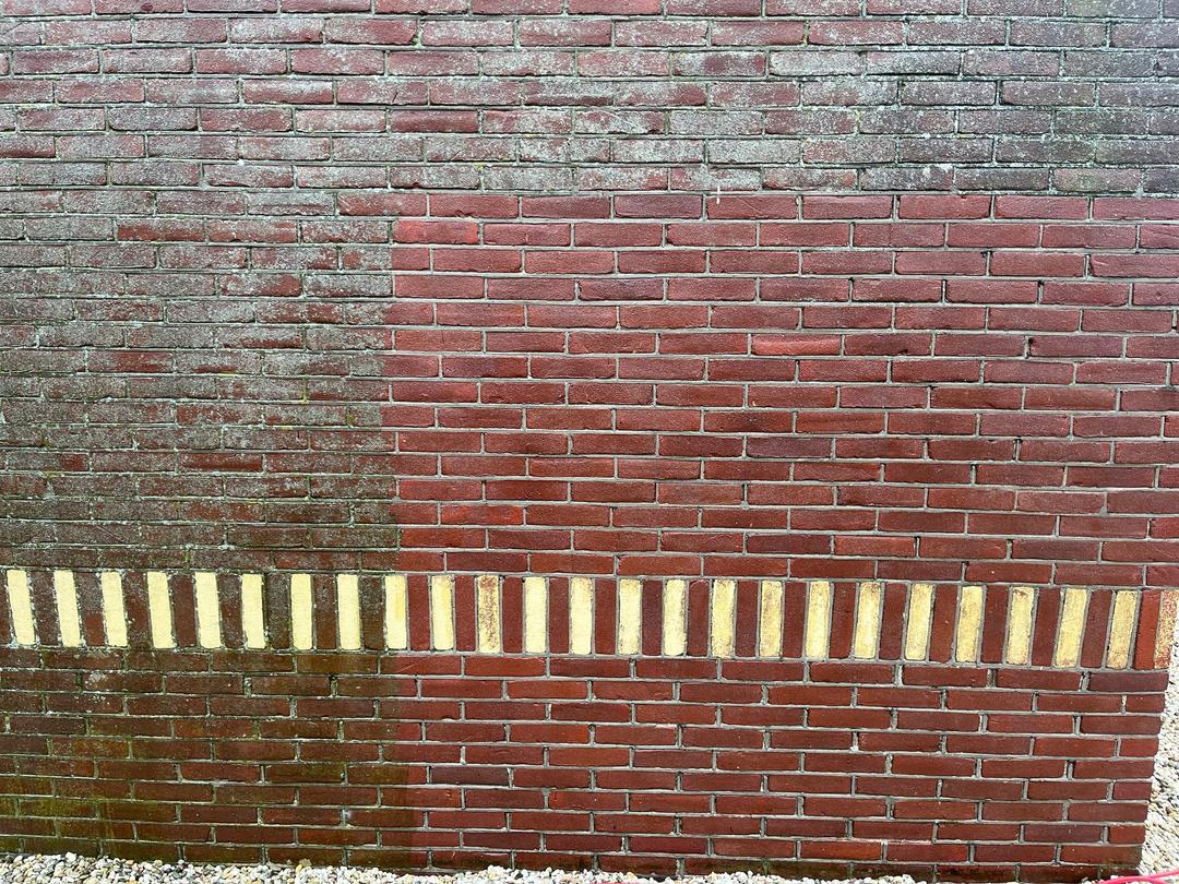 Bakstenen gevel, links nog grijs en vergroend, rechts weer schoon rood metselwerk