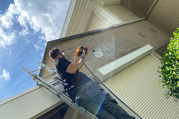 Medewerker op een ladder die een gevel reinigt